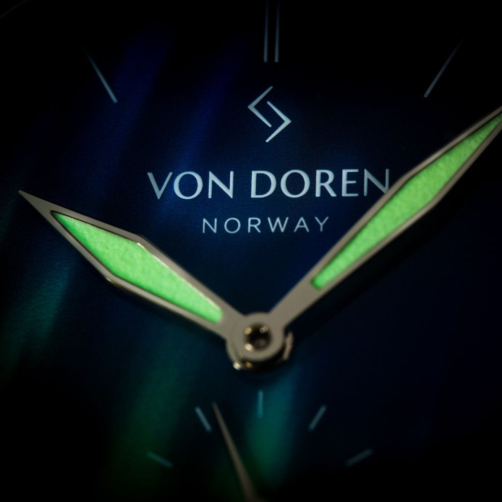Von Doren klokke med nordlys urskive mot mørk bakgrunn, premium produktfoto.