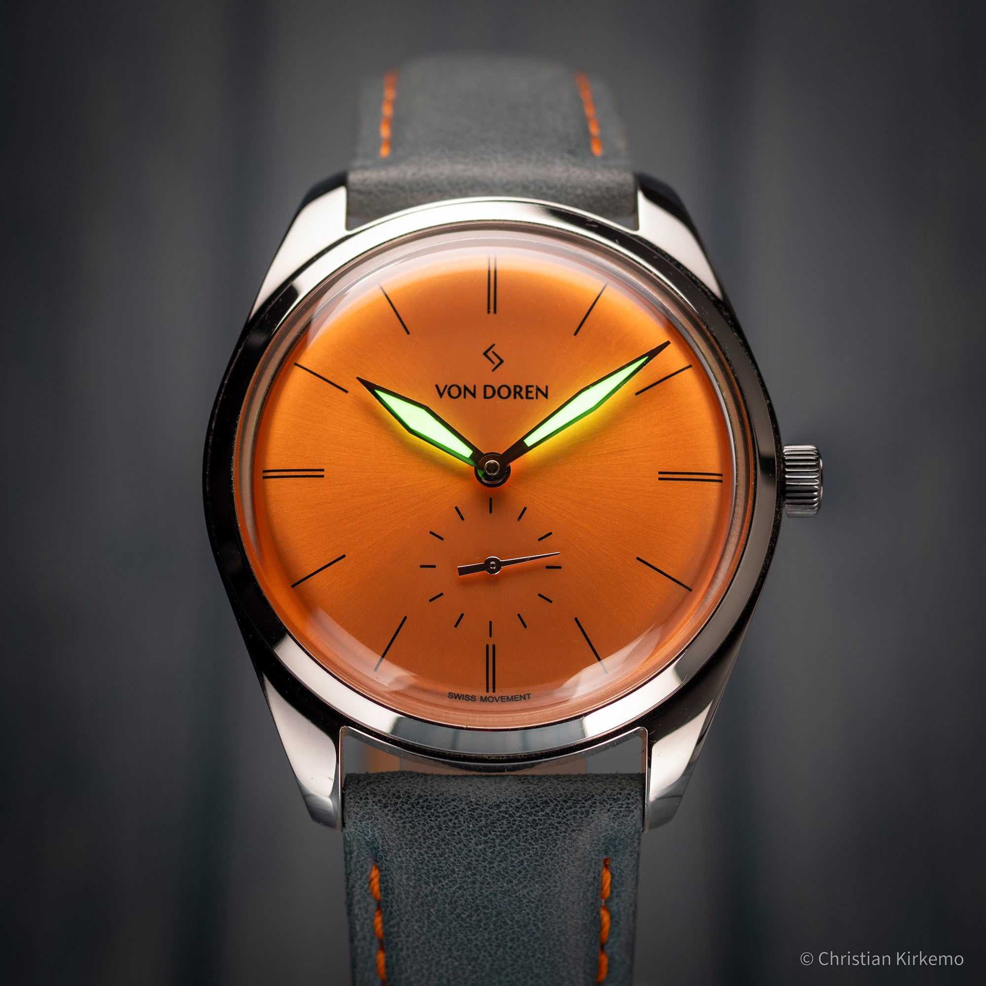 Von Doren klokke med oransje sunburst skive og blå reim.