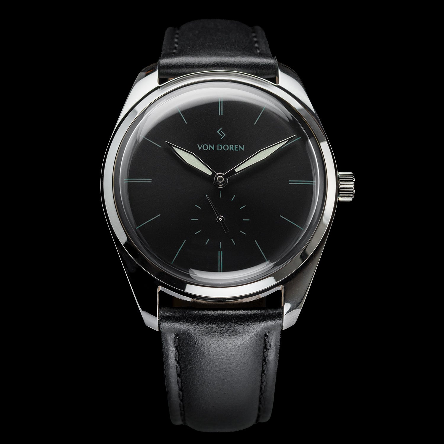 Von Doren-klokke med sort tallskive, sølvfargede visere og sort lærrem, mot mørk bakgrunn.