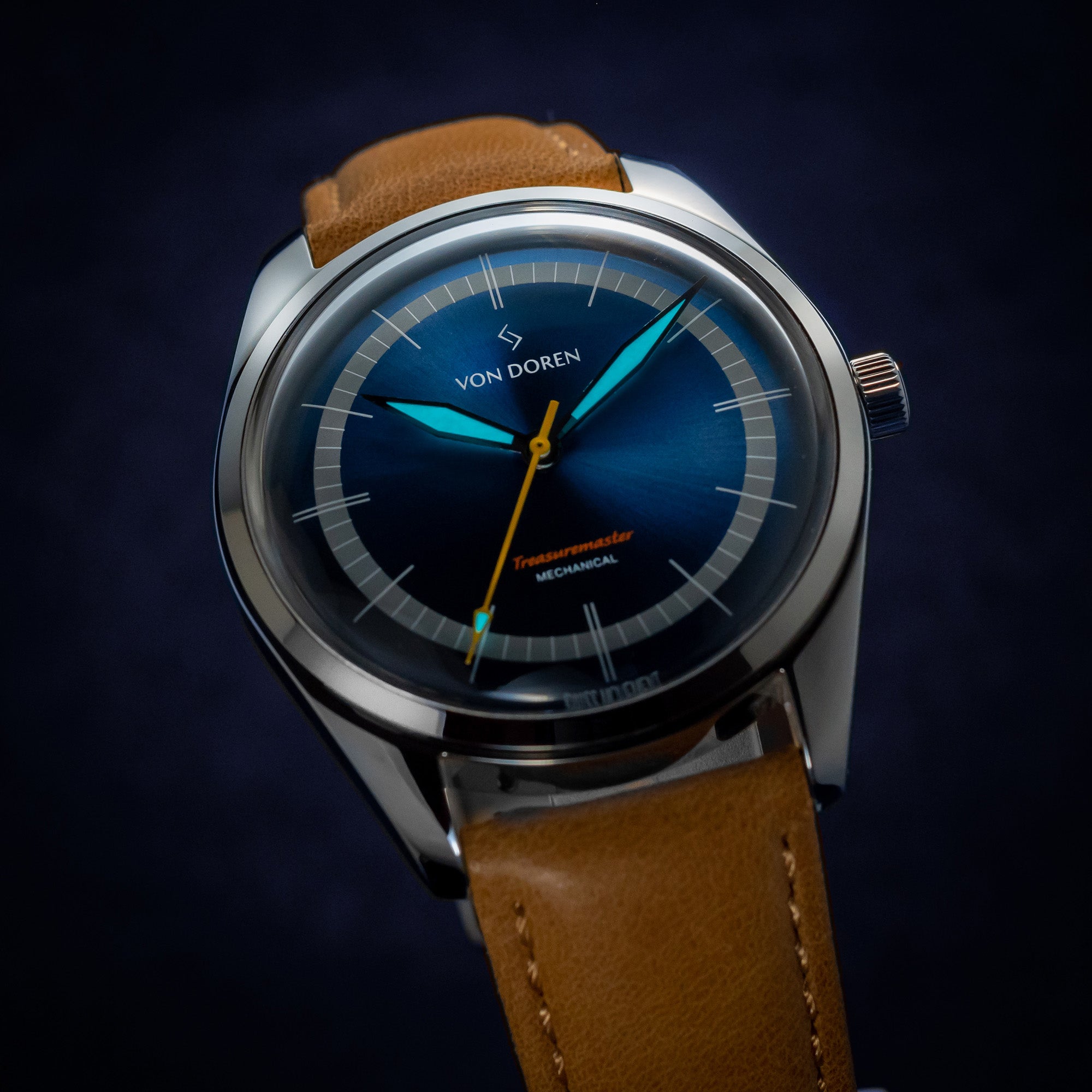Von Doren klokke med blå skive. Viserene lyser i mørket.