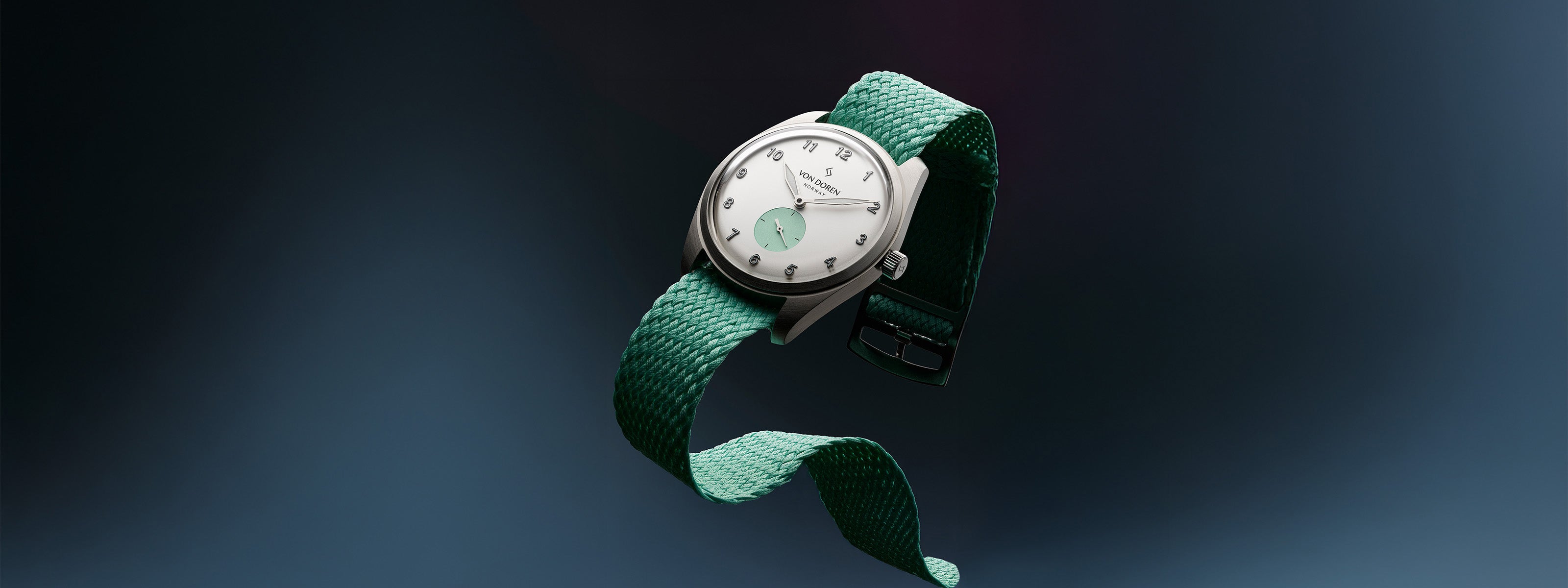 Von Doren Runde Candy Sugar med hvit urskive og grønn perlonrem som svever mot en mørk gradientbakgrunn."