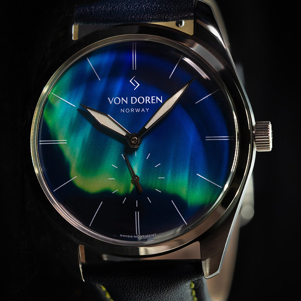 Von Doren dressklokke med nordlys urskive og blå skinnrem, produktfoto.