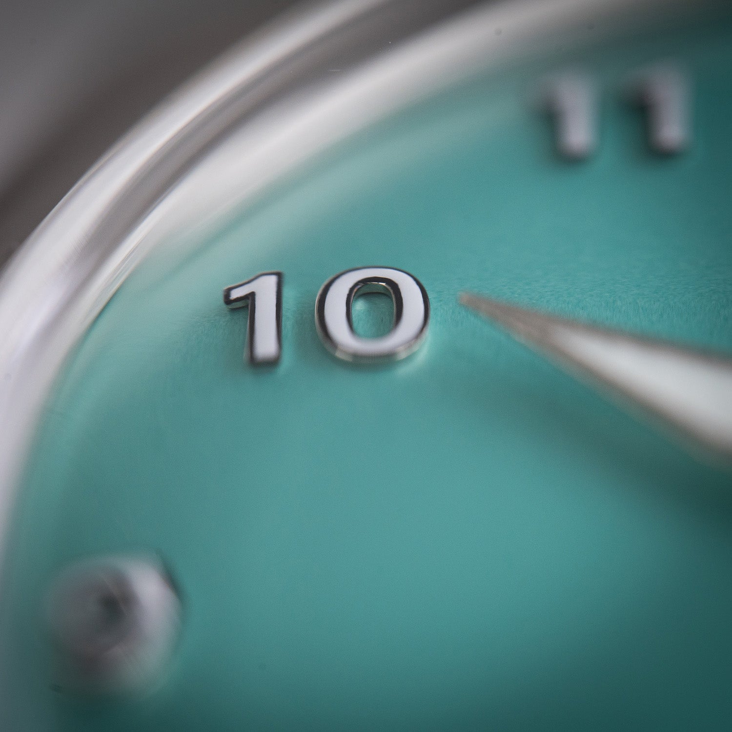 Makrobilde av Von Doren-klokke med mintgrønn tallskive, fokus på det opphøyde tallet 10 i sølv.