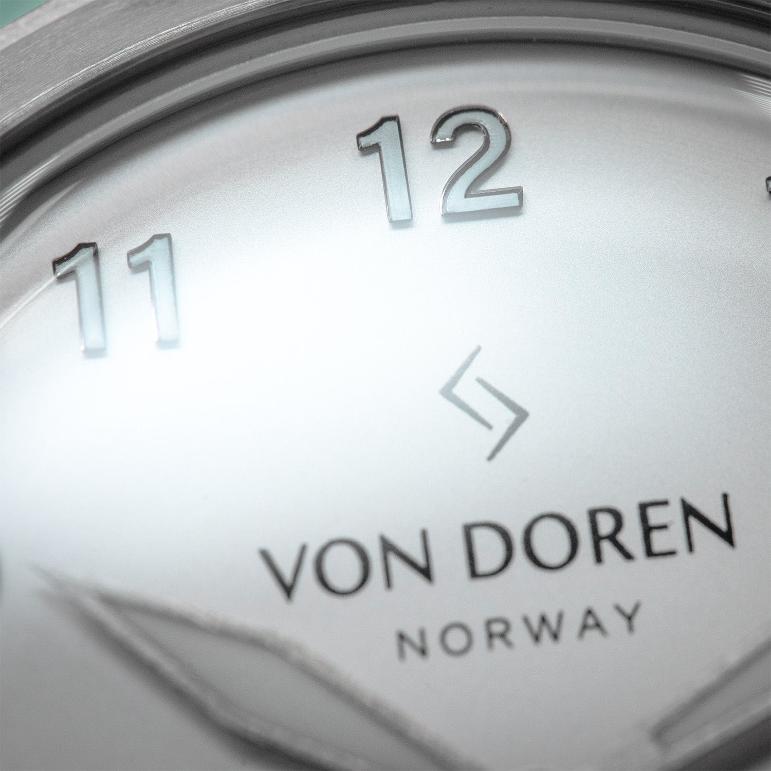 Nærbilde av Von Doren-klokke med sølvfarget tallskive, opphøyde tall og logoen “Von Doren Norway” under senteret.
