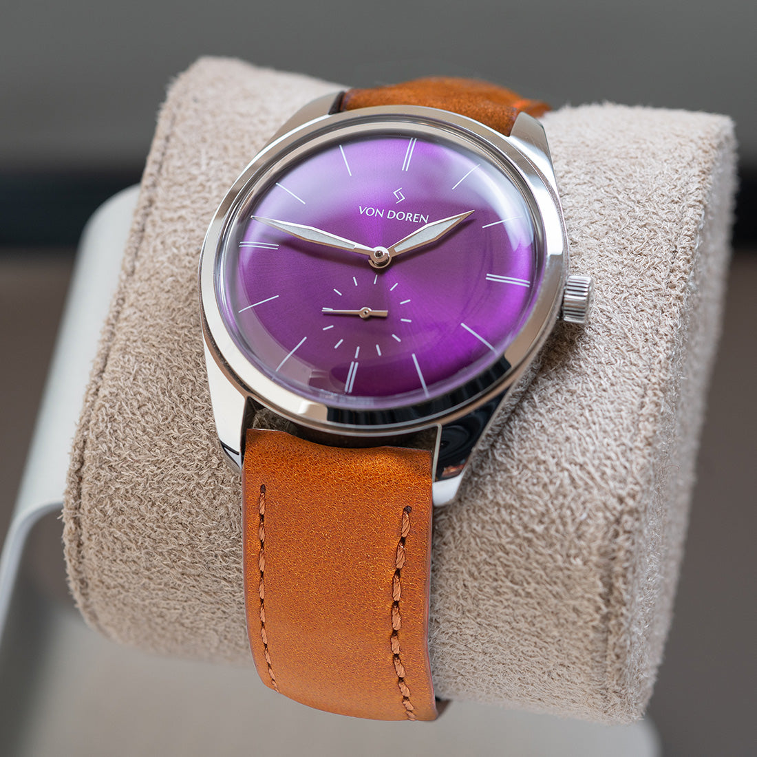 Runde - Purple, hvilende på en klokkepute med varm, brun skinnreim.