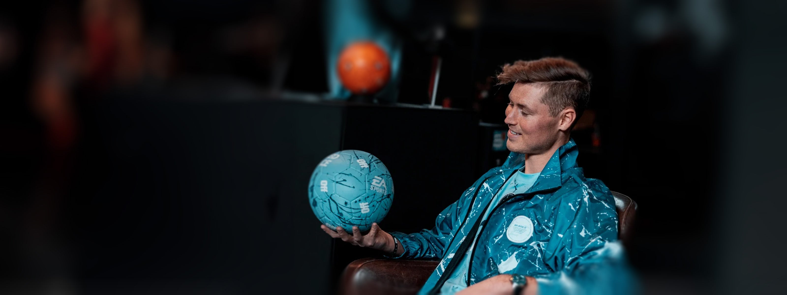 Tobias Becs holding a blue EA Sports football while wearing a Von Doren watch.